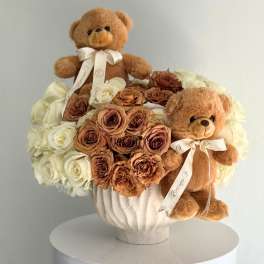 Bouquet of cream and brown roses with two teddy bears in a white vase