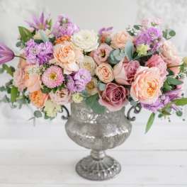 Pastel bouquet of roses and mixed blooms in a silver urn vase