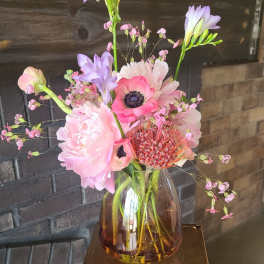 Pink and lavender flowers arranged in an amber glass vase