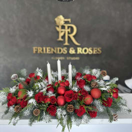 Red rose centerpiece with white candles, pinecones, and frosted evergreen