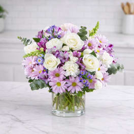 Bouquet of white roses and pink daisies in a clear glass vase
