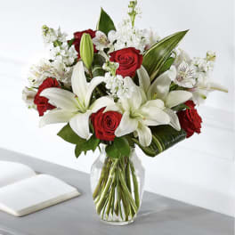Bouquet of red roses and white lilies in a clear glass vase