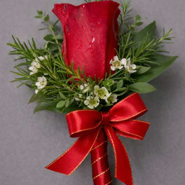 Single red rose boutonniere with white filler flowers and a red ribbon bow