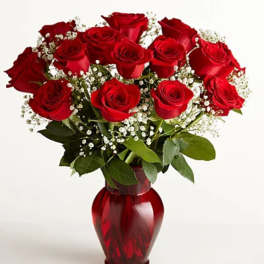 Red roses arranged in a red glass vase with white baby's breath
