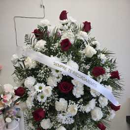 Standing funeral spray of red and white flowers with a memorial ribbon
