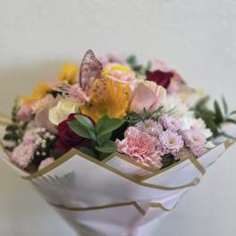 Mixed bouquet of pink, yellow, and white flowers wrapped in white paper