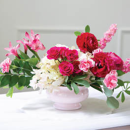 Pink and red floral arrangement in a pale pink vase
