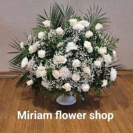 Large white floral arrangement in a low pedestal vase