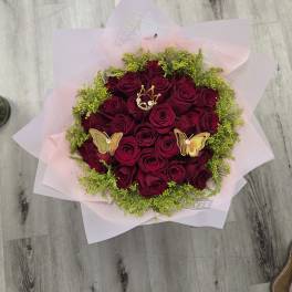 Bouquet of deep red roses with pink wrapping and butterfly picks