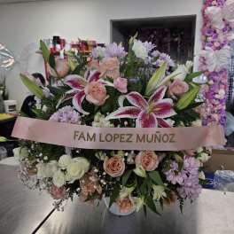 Large pink and white floral arrangement with a memorial ribbon