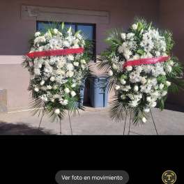 Two large white floral standing sprays on easels with pink ribbons