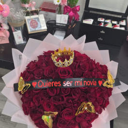 Heart-shaped bouquet of deep red roses with a crown and banner