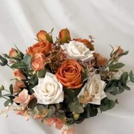 Bouquet of orange and white roses with greenery and a peach ribbon