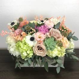 Mixed pastel floral arrangement in a white rectangular container