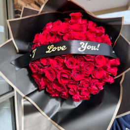 Large bouquet of red roses wrapped in black paper with a "I Love You!" ribbon