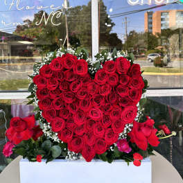 Heart-shaped red rose arrangement in a white box