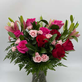 Pink and red roses with lilies in a glass vase