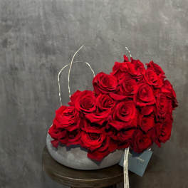 Red roses arranged in a gray oval vase on a round table