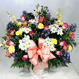 Mixed bouquet of daisies, roses, and carnations with a pink ribbon