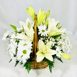 White lilies and daisies arranged in a wicker basket