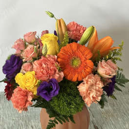 Mixed bouquet in a pumpkin-shaped vase with orange, pink, purple, and yellow flowers