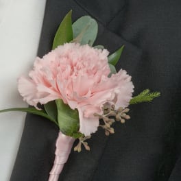 Pink carnation boutonniere with ribbon wrap on a dark suit lapel