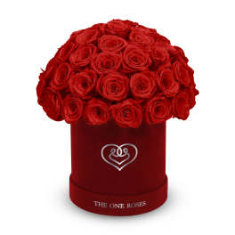 Red roses arranged in a round velvet box with a heart emblem