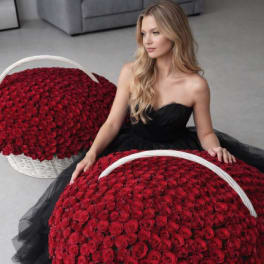 Woman in a black dress posed with two large baskets of red roses