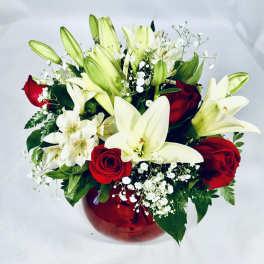Bouquet of white lilies and red roses in a red glass vase