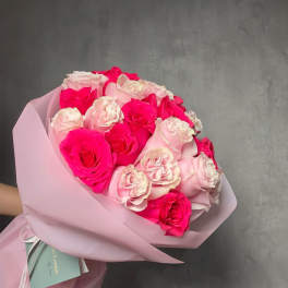 Hand-tied bouquet of bright and pale pink roses wrapped in soft pink paper