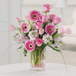 Pink roses and gerbera daisies in a clear glass vase