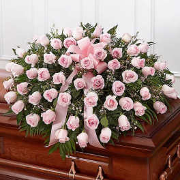 Pink rose casket spray with ribbon on a wooden casket