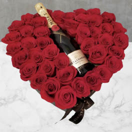 Heart-shaped bouquet of red roses with a champagne bottle in the center