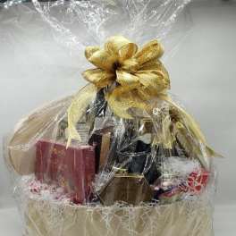 Gift basket with bottles and boxed treats wrapped in clear cellophane and a gold bow