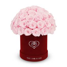 Pink roses arranged in a red velvet hat box