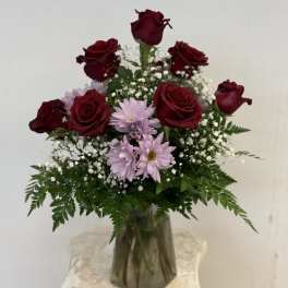 Bouquet of red roses and light purple daisies in a glass vase