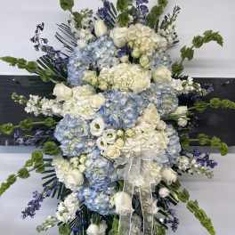 Large white and blue floral spray with ribbon on a black stand