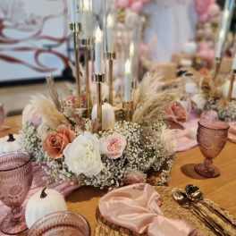 Low floral centerpiece with roses, baby's breath, and candles on a table