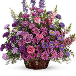 Purple and pink mixed flower basket arrangement in a wicker basket