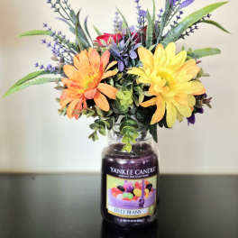 Artificial flowers arranged in a candle jar vase
