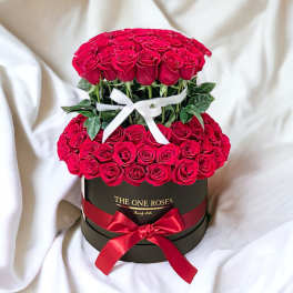 Two-tier arrangement of red roses in a black round box with ribbons
