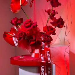 Red roses with heart-shaped anthuriums and a honey ribbon in a gift box