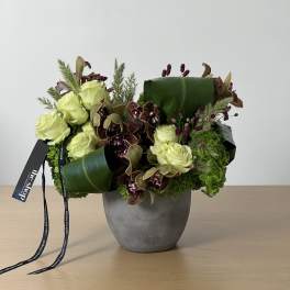 Green and burgundy floral arrangement in a gray vase