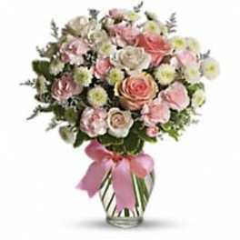 Pink and white rose bouquet in a clear glass vase with a pink ribbon