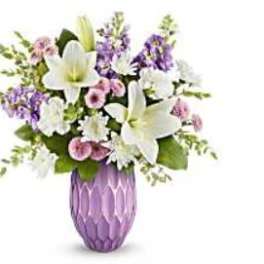 White lilies and purple flowers arranged in a purple vase