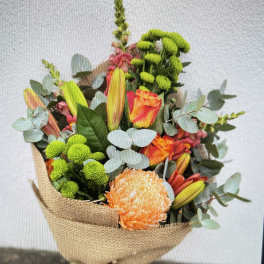 Bouquet of orange and pink flowers wrapped in burlap