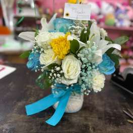 Bouquet of white and blue flowers with a yellow center bloom in a vase