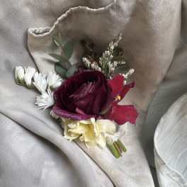 Small bouquet with burgundy, cream, and white flowers on beige fabric