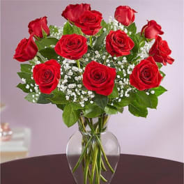 Red roses arranged in a clear glass vase with baby's breath