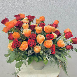 Bouquet of red and orange roses in a white vase